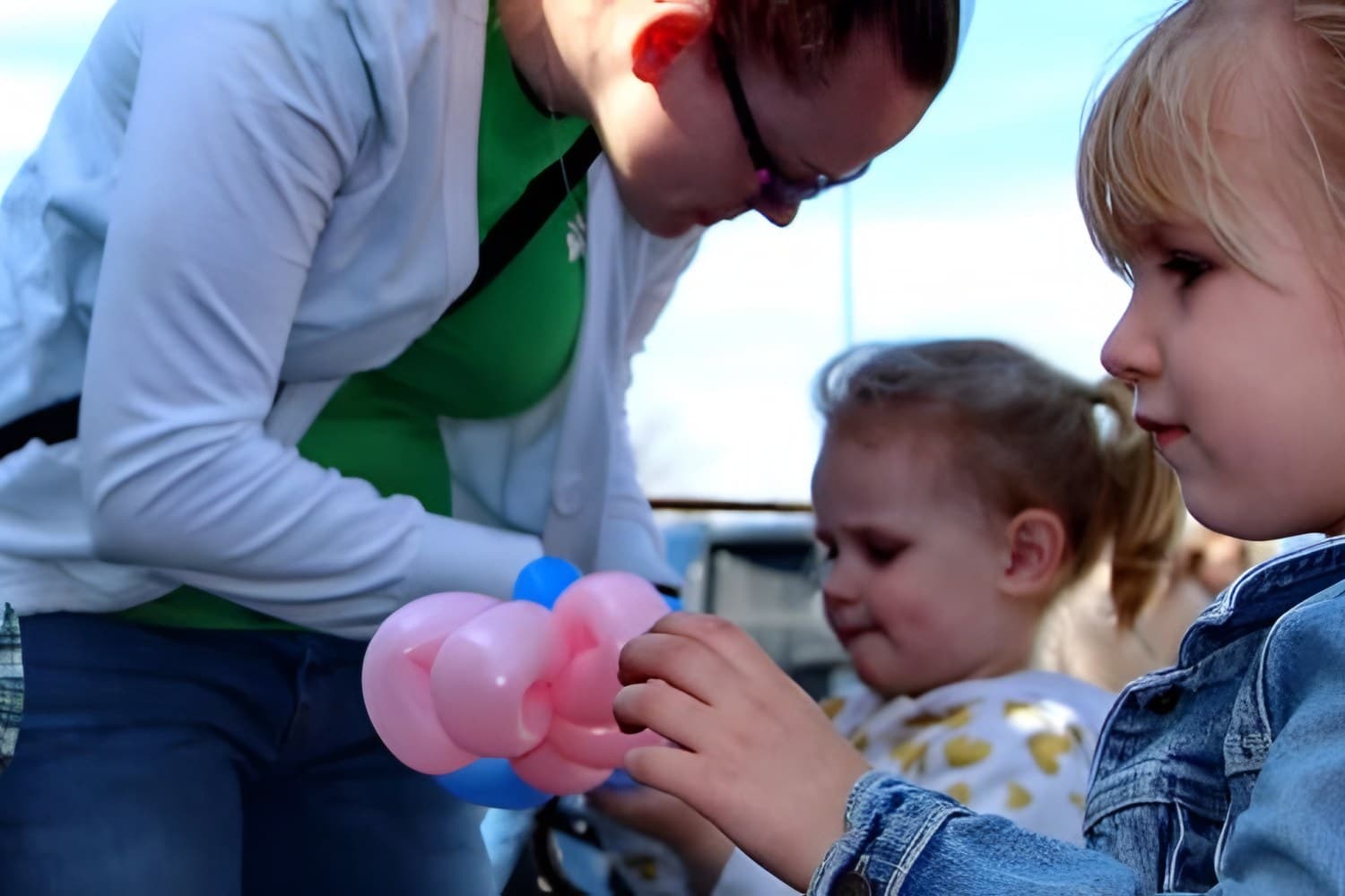 A volunteer twists a balloon animal for a little girl