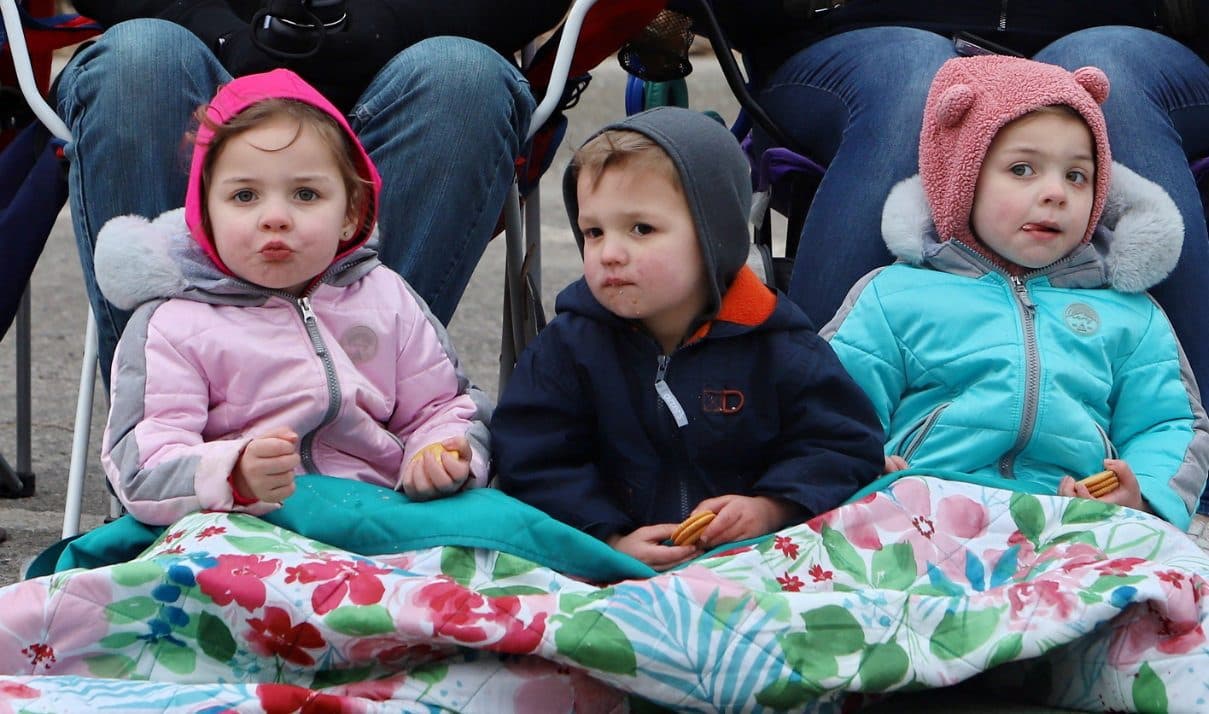 Three bundled-up toddlers watching the parade
